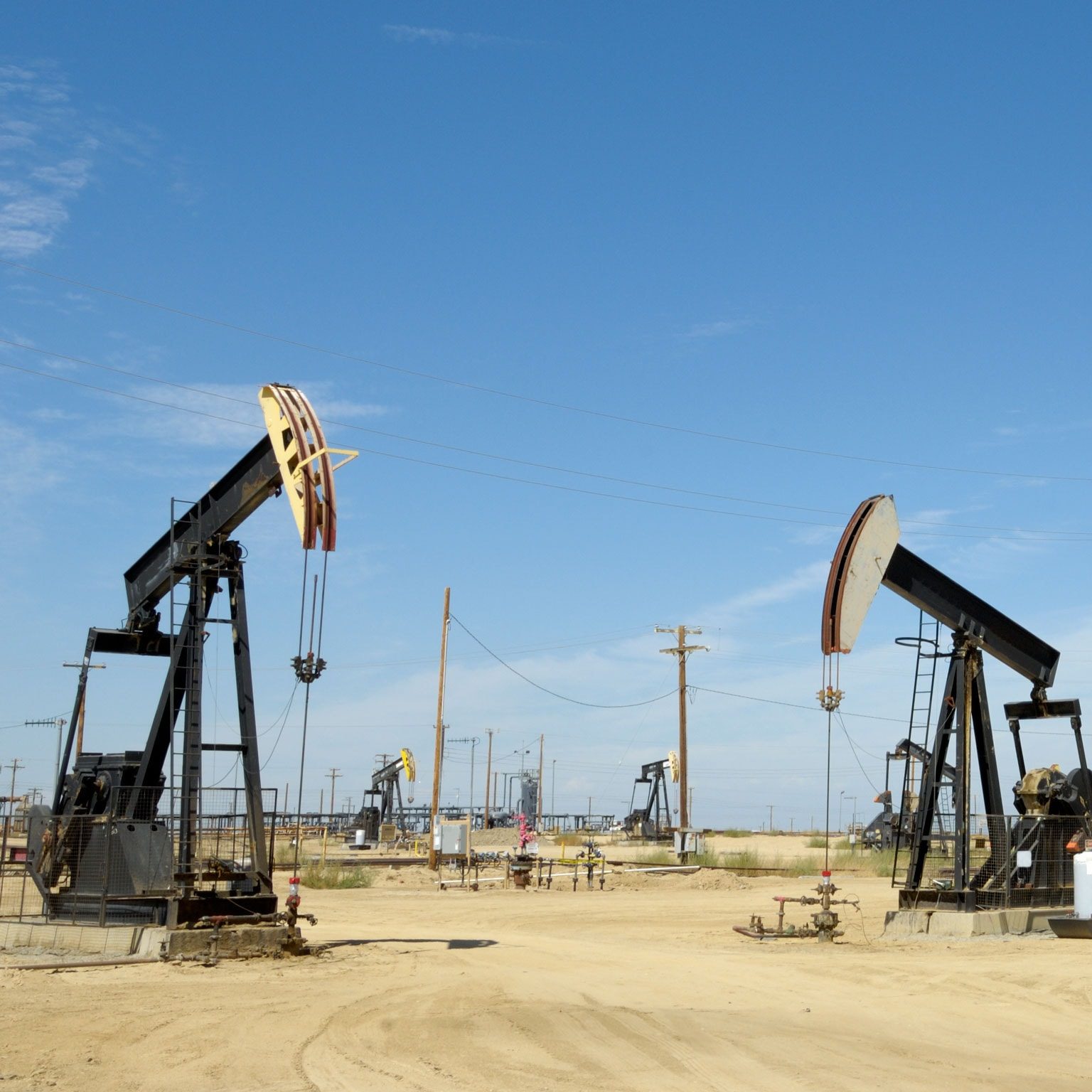 Oil pump jacks in a producing field under a blue sky